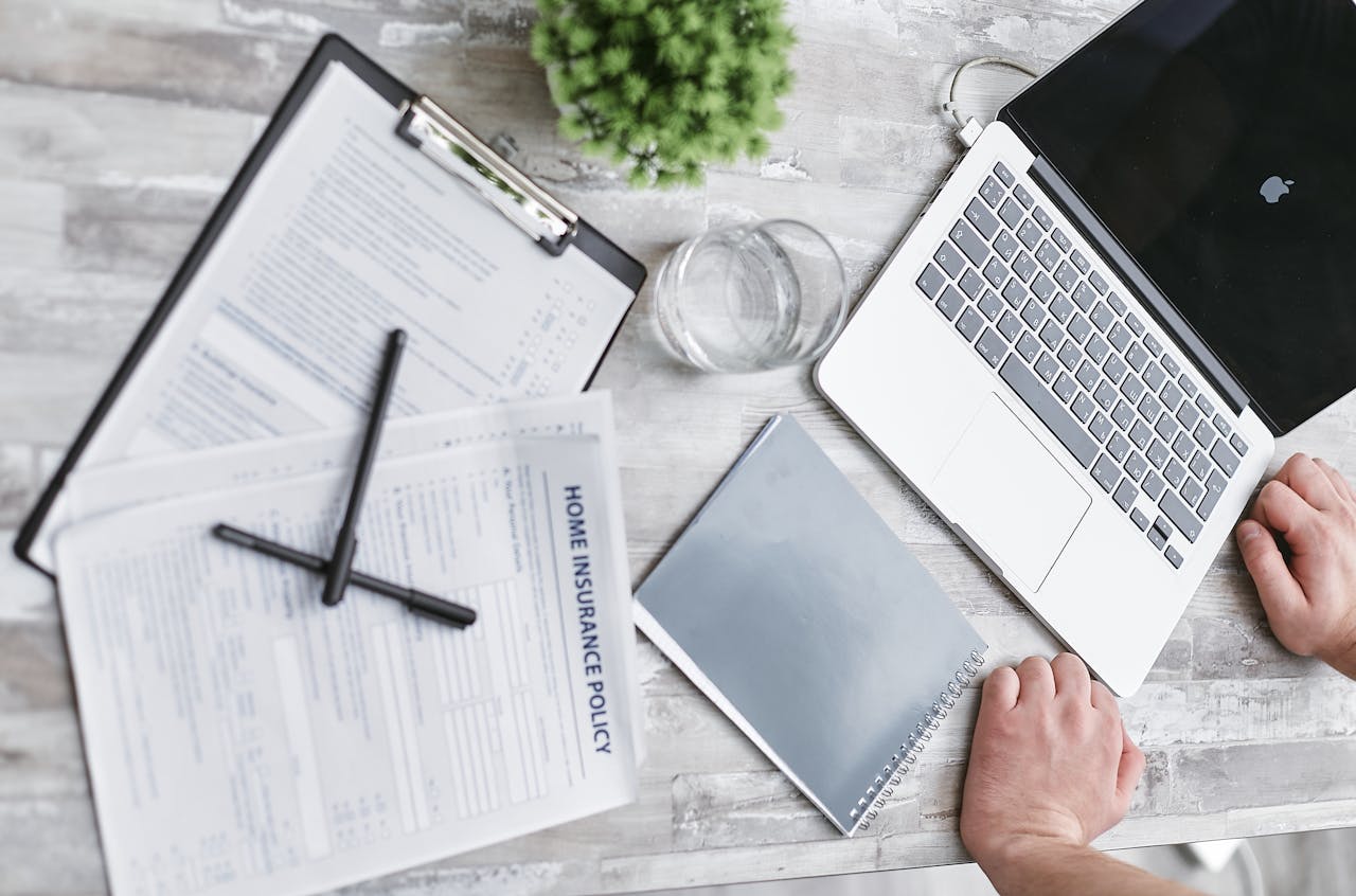 Services Top view of home insurance forms, laptop, and documents on a desk, conveying a professional office setting.